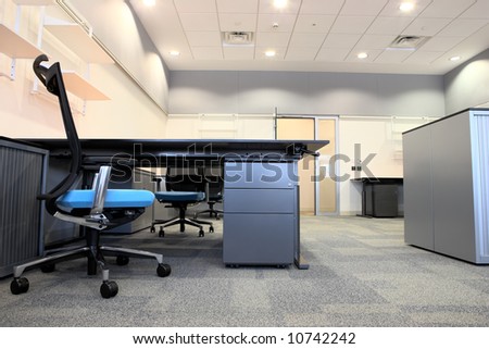 Empty office with new modern office furniture, including desks, cupboards, filing cabinets and chairs. Two blue chairs facing out. HDR type image
