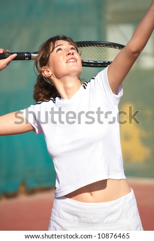 Young woman playing tennis in the sun. About to serve the ball