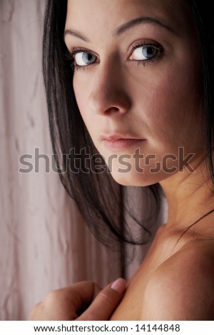 Sexy young adult Caucasian woman with black hair, smooth skin and blue contact lenses in her eyes.