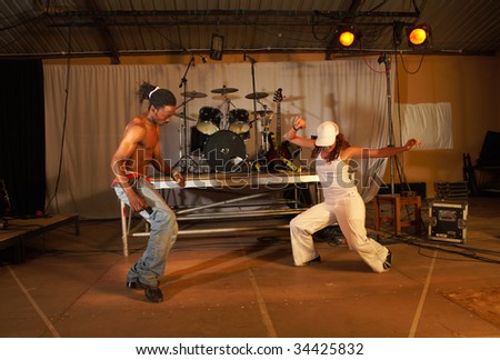 Two freestyle hip-hop dancers a man and a woman at a training session on stage with instruments in the background