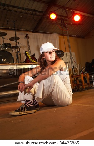 Single Caucasian freestyle hip-hop dancer at a training session on stage with instruments in the background