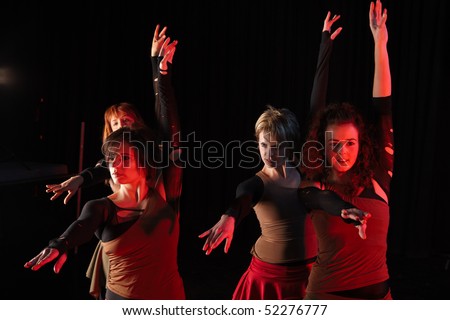 A group of female freestyle hip-hop dancers in a dancing training session. Lit with spotlights