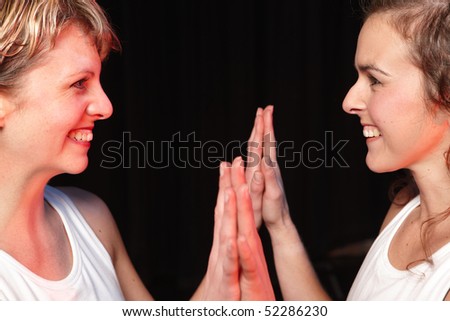 A group of two Caucasian female freestyle hip-hop dancers in a dancing training session. Lit with spotlights