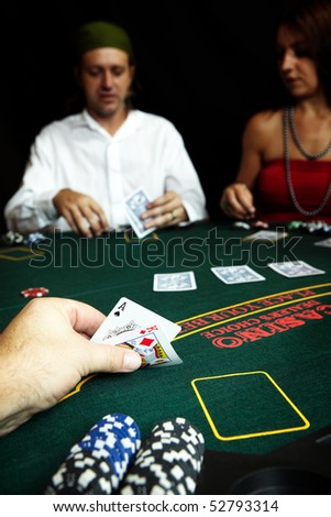 Ace of clubs and King of Diamonds in hand in a poker hand with high value chips on the table