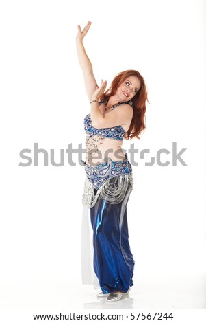 Lithe adult caucasian belly dancer with red hair and a blue belly dancing outfit performing steps on a white background. Not Isolated