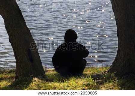 Man sitting near lake and watching solar patches of light.