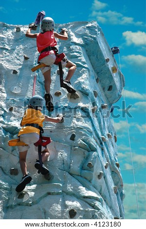 A team (two kids) climbing the top of a rock wall