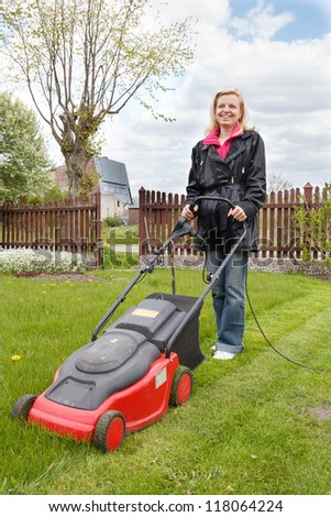 Woman mowing a garden with an electric lawn mower