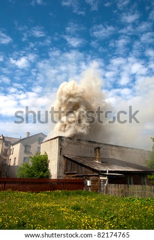 fire in city building, with white smoke to the blue sky