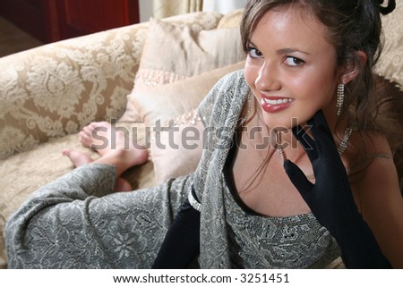 Young brunette lying on couch in evening wear
