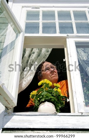 Elderly woman looking out of an old fashioned window