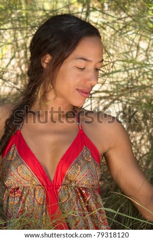 A beautiful, exotic, Hawaiian woman, framed by tall grass. Vertical image orientation.