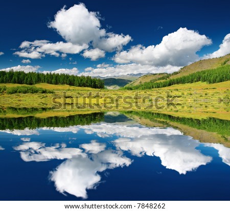 Landscape with forest and blue sky reflected in water