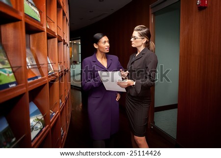 Two women discussing project in corporate building