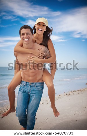 Man carrying woman on a beach, both smiling