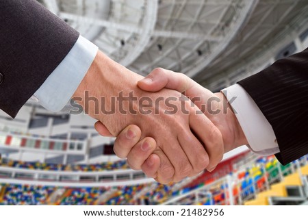 Two business men shaking hands in stadium