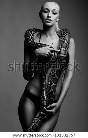 black and white picture of sexy young woman in bikini posing with python