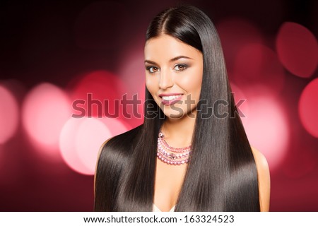closeup portrait of beautiful girl with straight long dark hair against shining pink background