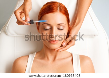 closeup portrait of lovely redheaded woman with closed eyes and hand with medicine dropper
