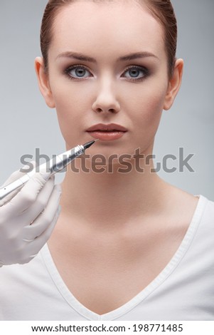closeup portrait of lovely young woman getting permanent makeup on her lips