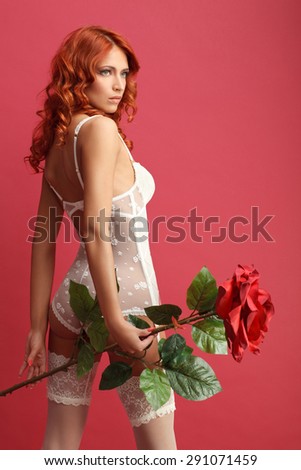 side view of sexy girl in white lingerie holding a huge decorative rose against red wine background