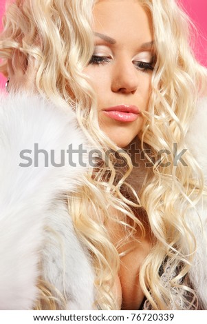 pretty young woman wearing fur coat against pink background