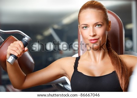 closeup portrait of young woman doing workout on exercise machine in gym