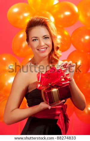 portrait of happy woman opening gift box over pink background