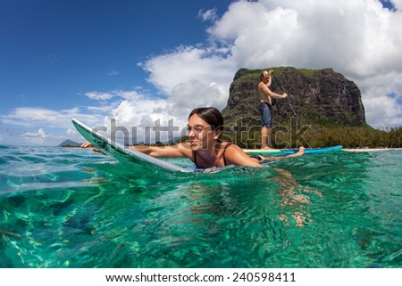young muscular surfer with long white hair l watching the girl which surfing in the open ocean