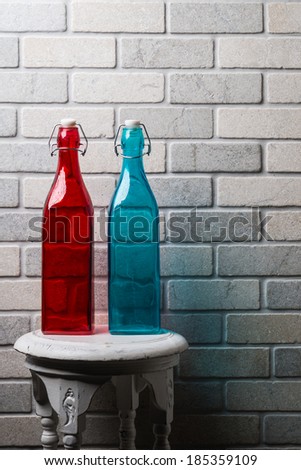 Colored glass bottles standing/Stone, glass and wood/Red and blue glass bottles