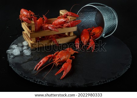 Wooden crate and bucket of red lobsters with ice on black background Photo stock © 