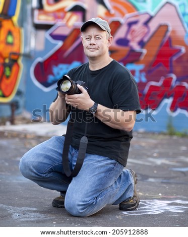 Man in cap taking photos near graffiti wall