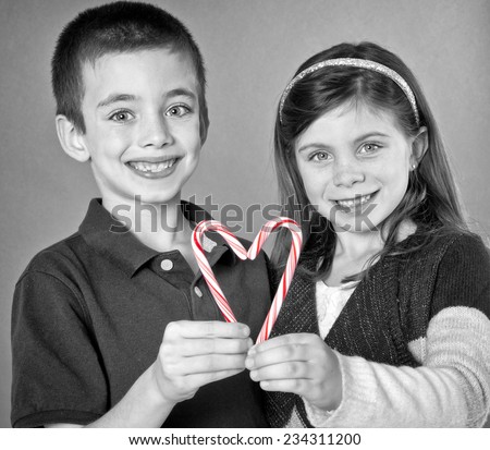 Boy and girl smiling with a candy cane heart in black and white with colored heart