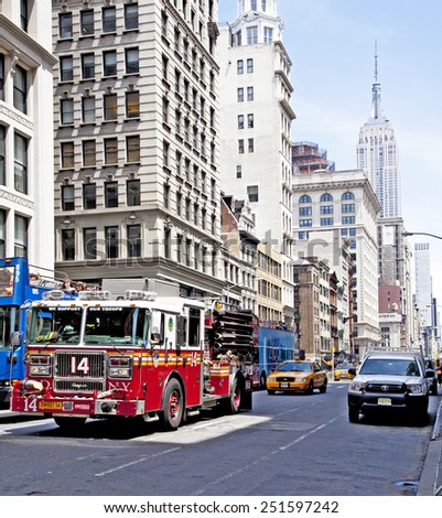 NEW YORK CITY - JUNE 28, 2014: Streets of NYC mid afternoon with FDNY firetruck and taxi cab in view and the Empire State Building.