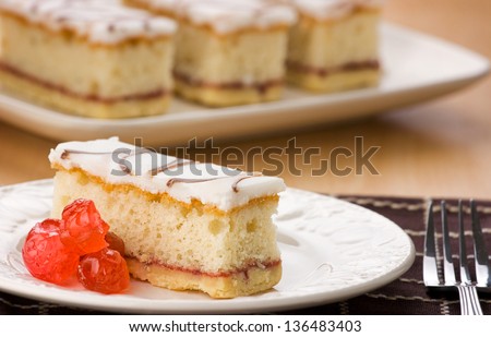 Sponge Cake with Fondant Topping And Layered With And Jam. Glazed Cherries On A White Plate