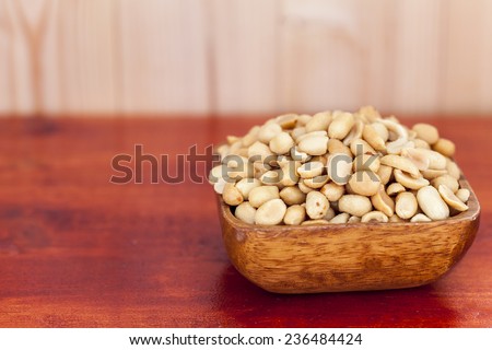 Salted, roasted, peanuts in a wooden bow, on white background