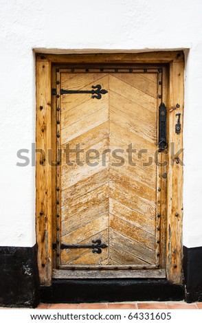 Antique oak door with black step and white wall.