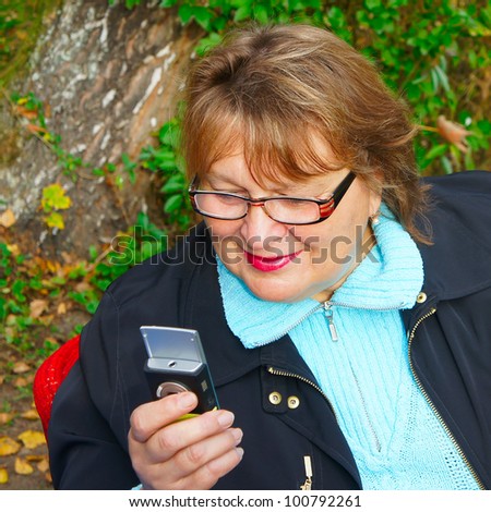 Mature woman  dialing a number on her cell phone.