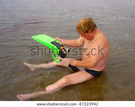 Elderly man with tube, mask and fins getting ready for snorkeling