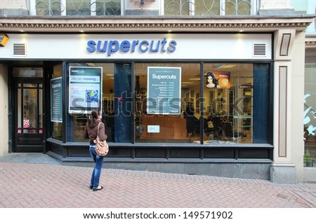 BIRMINGHAM, UK - APRIL 19: Woman watches Supercuts window on April 19, 2013 in Birmingham, UK. Supercuts is a cheap haircut salon franchise with 180+ salons in the UK and 2000+ worldwide.