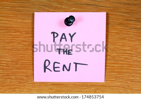 Sticky note with a message - pay the rent. Bulletin board.