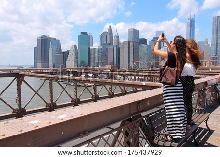 NEW YORK, USA - JULY 5, 2013: Women take photos from Brooklyn Bridge in New York. Almost 19 million people live in New York City metropolitan area.