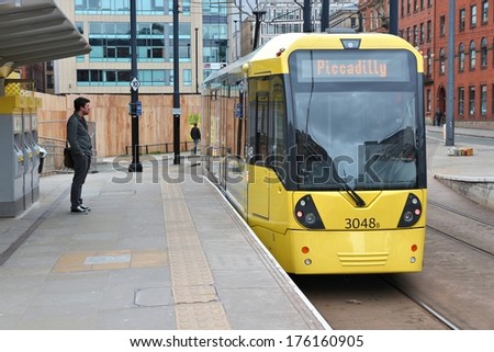 MANCHESTER, UK - APRIL 21, 2013: People board Manchester tram in Manchester, UK. Manchester Metrolink serves 21 million rides annually (2011).