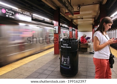 NEW YORK, USA - JULY 1, 2013: People wait at a subway station in New York. With 1.67 billion annual rides, New York City Subway is the 7th busiest metro system in the world.