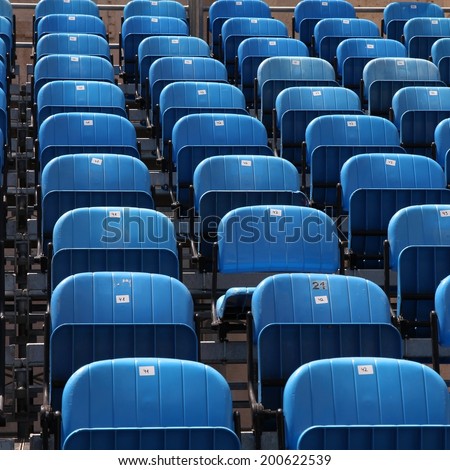 Blue rows of chairs at an outdoor concert. Audience seats. Square composition.