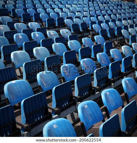 Blue rows of chairs at an outdoor concert. Audience seats. Square composition.