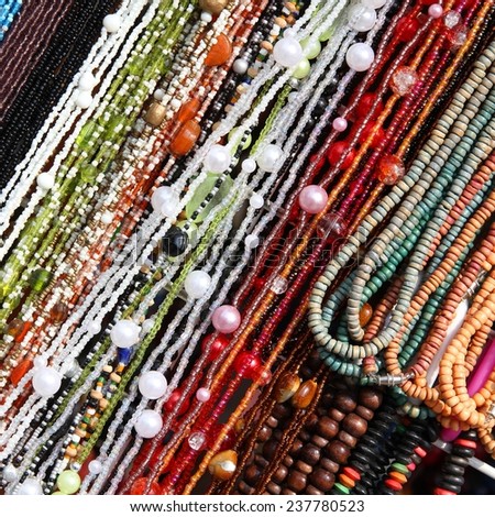 Background of colorful beads - necklaces at a store. Abstract jewellery. Square composition.