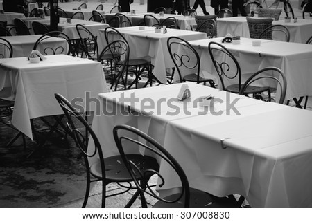Outdoor city restaurant tables. Parma, Italy. Black and white tone.