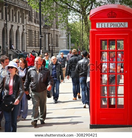 LONDON, UK - MAY 13, 2012: People walk past telephone booth in London. With more than 14 million international arrivals in 2009, London is the most visited city in the world (Euromonitor).