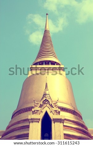 Thai Buddhist temple in Bangkok, Thailand. Golden stupa - Phra Sri Rattana Chedi, belongs to Wat Phra Kaew (famous Temple of the Emerald Buddha). Cross processed color tone - retro filtered style.